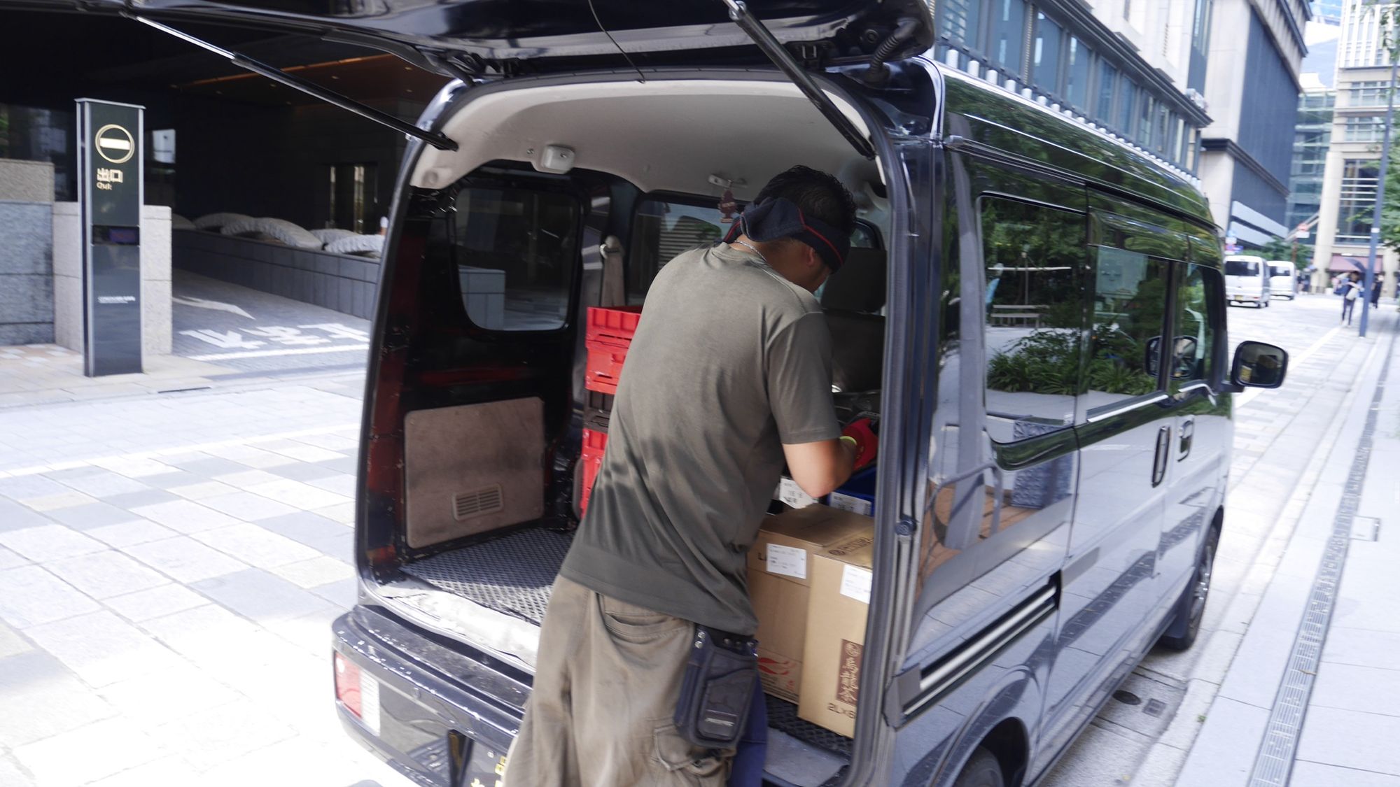 軽バンの荷室から荷物を運び出すところ